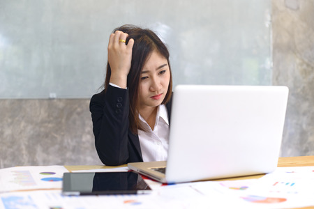 Stressed business woman working on a laptop at office. workplace strategy and entrepreneurship Concept.の写真素材