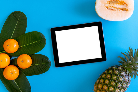 Topview of orange,pineapple, cantaloupe with desktop with blank white tablet on plates blue background. topview or flat lay fruit.の写真素材