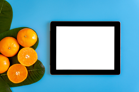 Topview of orange with desktop with blank white tablet on plates blue background. topview or flat lay fruit.の写真素材