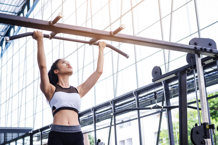 fitness woman exercise workout with exercise-machine pull up on bar in fitness center gym. healthy...