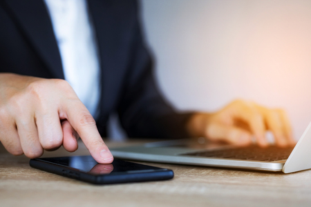 Closeup hand of business woman using smart mobile phone at officeの写真素材
