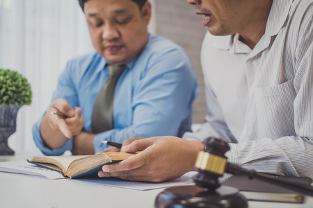 Male lawyer teaching new lawyer and  discussing with contract papers and wooden gavel on tabel in courtroom. justice and law ,attorney, court judge, concept.の写真素材