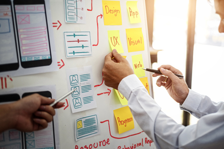 UX designer creative group working about planing mobile application project with sticky notes. User...