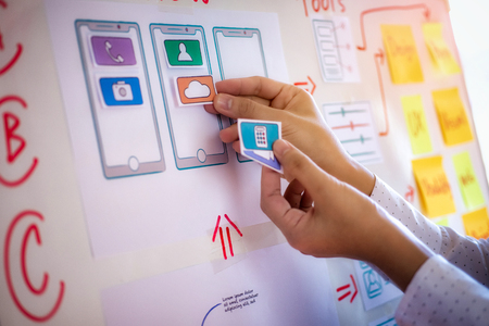 Young creative graphic planning with sketch drawing for application developing in office. User...
