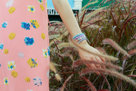 A Woman walking through the wind and put the hand on the grass.の写真素材