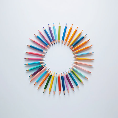 This image presents a top-down view of many colored pencils arranged in a circular formation on a plain white surface. The pencils, displaying a broad range of colors, have their tips directed towards the center, forming a neat and organized pattern. The flat lay perspective highlights the collection of art supplies and their colorful diversity.の素材