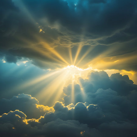 Intense golden sun rays burst through a dense canopy of dark, moody clouds in the sky. The light creates a dramatic contrast, illuminating the edges of the clouds and casting long, radiant beams. The sky exhibits a mix of dark blues and yellows, highlighting the powerful and awe-inspiring natural phenomenon.の素材