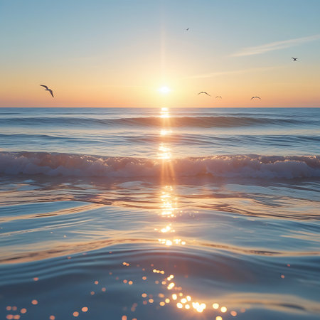 Gentle ocean waves catch the warm light of the setting sun, creating a shimmering, sparkling effect on the water's surface. Several seagulls are silhouetted against the colorful sky as they fly overhead. The scene is tranquil and beautiful, with the sun casting long reflections across the vast expanse of the sea.の素材
