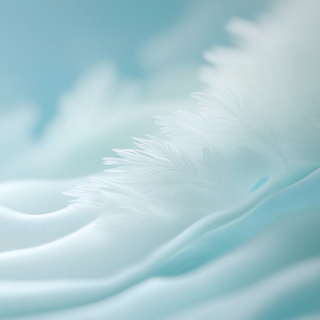 This close-up image showcases the fine, wispy barbs of a white feather emerging from the soft, undulating waves of translucent blue fabric. The lighting is gentle and diffused, highlighting the delicate textures and the ethereal quality of the scene. The composition creates a sense of lightness, softness, and serene natural beauty.の素材