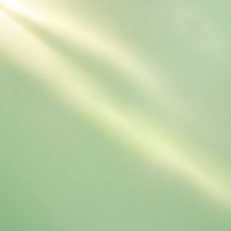 Diagonal beams of soft, pale yellow light cut across a muted green background with a subtle, almost imperceptible texture. The light creates a gentle gradient, transitioning from brighter areas where the rays fall to darker, softer areas. The image evokes a sense of calm and natural illumination.の素材