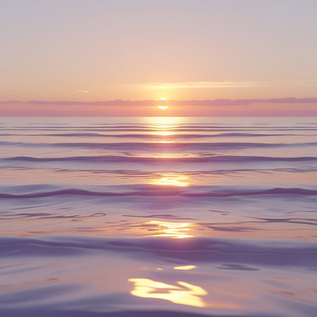 A tranquil ocean vista at sunset or sunrise, characterized by soft pastel colors. The sun, a warm orb, casts a glowing reflection on the rippling water. The sky is a delicate blend of pinks and oranges, with a few faint clouds. The foreground shows the gentle undulation of the sea.の素材