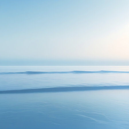 A minimalist and tranquil seascape with a vast expanse of calm ocean. Subtle, smooth waves create gentle lines across the water's surface, leading to a pale blue, softly gradient sky. The scene evokes a sense of profound peace, stillness, and quiet beauty.の素材