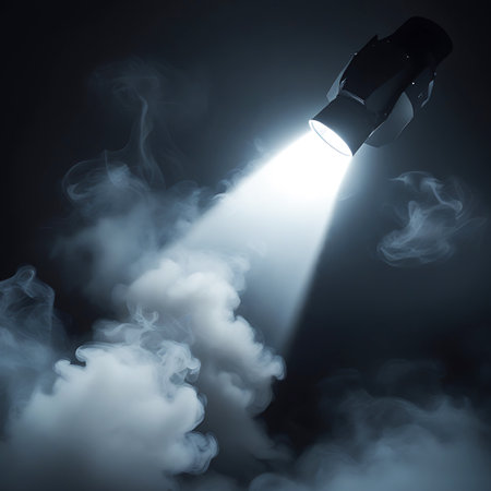 An angled beam of bright white light emanates from a dark spotlight fixture, cutting through a dark space filled with swirling white smoke. The light source is positioned to the right and above, casting a sharp beam that illuminates the textured, diffused smoke. The overall effect is dramatic and atmospheric, suitable for stage or event visuals.の素材