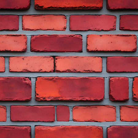A detailed close-up view of a red brick wall with gray mortar. The bricks are varied in color from deep red to orange-red, showing some imperfections and a rough texture. The gray mortar fills the gaps between the rectangular bricks, creating a repeating pattern. This image is suitable for use as a background or texture for various design projects.の素材