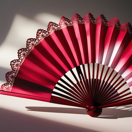 A detailed shot of a vibrant red fan, featuring a scalloped edge of delicate white lace. The fan is partially open, revealing its ribbed structure and the contrast between the red fabric and lighter interior. Dramatic lighting creates strong shadows, emphasizing the fan's curves and texture.の素材
