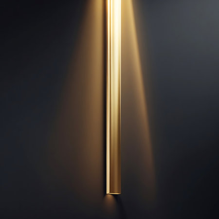 A single, vertical beam of golden light shines downwards against a dark, textured background. The light creates a soft gradient and subtle shadows, highlighting the minimalist and elegant aesthetic. This abstract image evokes a sense of focus, purity, and understated power.の素材