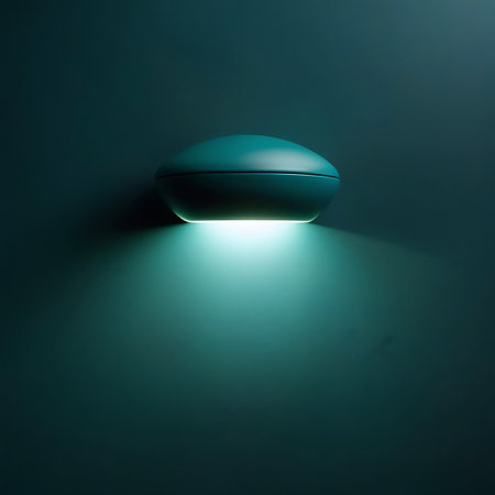 A modern, oval-shaped wall sconce in a deep teal color is mounted on a matching teal wall. The fixture emits a soft, bright white light downwards, creating a luminous glow and subtle shadows on the wall below. The design is minimalist and elegant, suggesting a contemporary interior design element.の素材