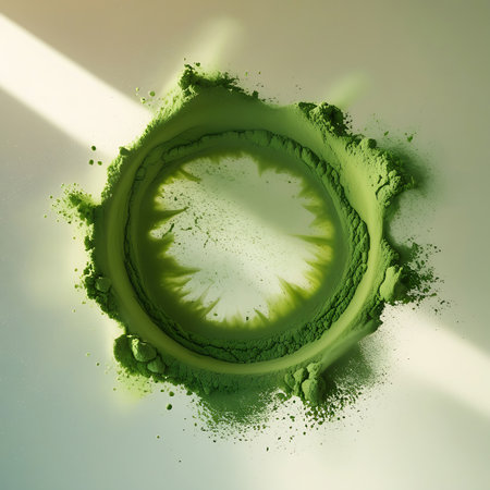 A dynamic splash of vibrant green matcha powder forms an irregular circular shape on a bright, light-colored surface. Fine particles and dust are scattered around the edges, suggesting a recent impact or movement. The overhead perspective highlights the organic, abstract form.の素材