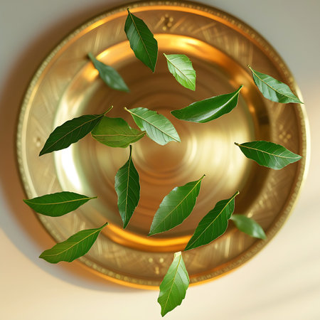 A top-down view shows multiple fresh green leaves scattered across the surface of a decorative brass plate. The plate is richly detailed with intricate embossed patterns and a textured rim, reflecting the light with a warm, golden sheen. The leaves, with their distinct veins, are arranged in a seemingly random yet aesthetically pleasing manner, some overlapping slightly. The background is a soft, neutral tone, emphasizing the central elements.の素材