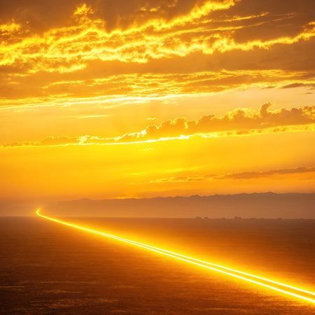 A dramatic sunset paints the sky in fiery oranges and yellows. A glowing line of light stretches across the vast desert horizon, creating an ethereal scene.の素材