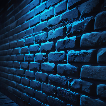 A close-up view of a dark, textured brick wall with subtle blue lighting casting shadows and highlighting the rough surface.の素材