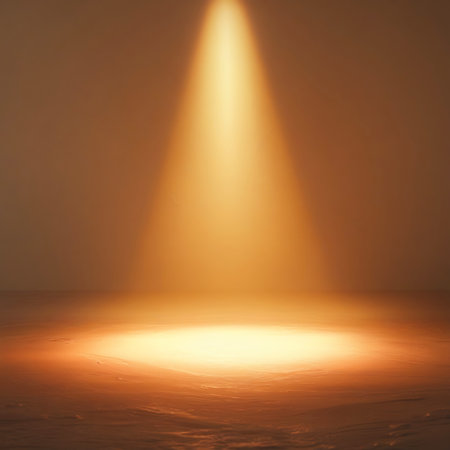 A bright, warm spotlight beam shines down from above, creating a luminous circle of light on a textured surface below.の素材