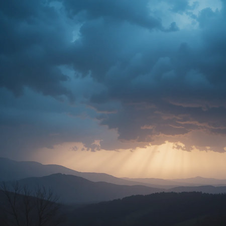 Dramatic sunset with golden rays of light piercing through dark blue clouds over layered mountain ridges.の素材