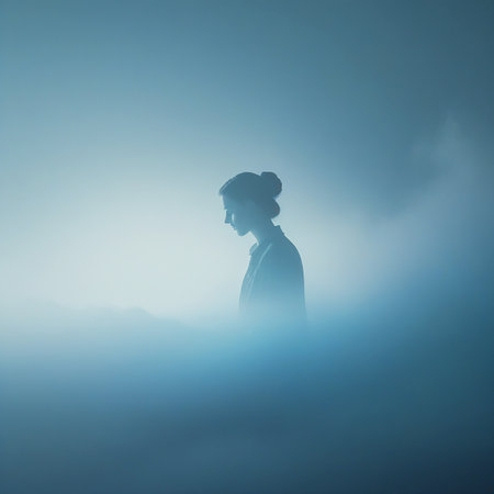 A woman's silhouette is seen in profile, head down, surrounded by soft blue fog and mist, creating an atmospheric and introspective mood.の素材
