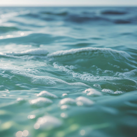The image captures a serene view of the ocean with gentle waves rolling towards the shore. The water is a beautiful shade of turquoise, reflecting the sunlight. The sky is clear, adding to the tranquil atmosphere. The waves create a soothing pattern, inviting a sense of peace and relaxation.の素材