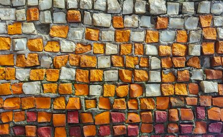 The texture of the old mosaic of small stones of white, orange, red, yellow