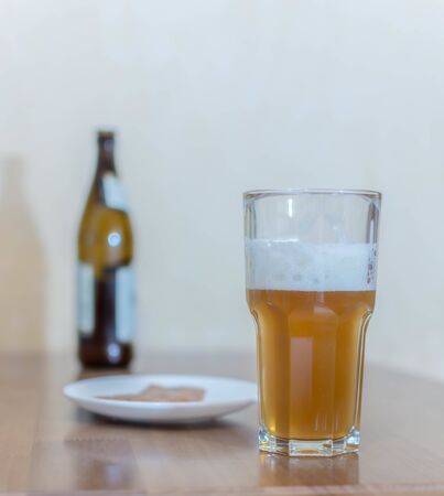 Beer in a glass on a wooden table in the background a bottle with beer and a fish in a plateの写真素材