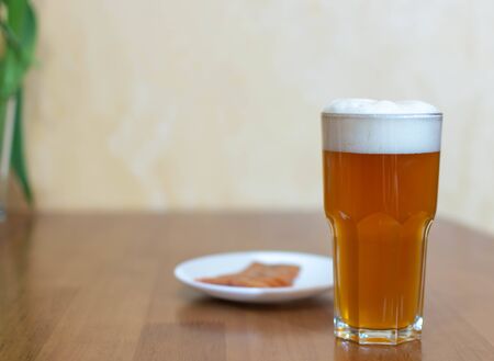Beer in a glass on a wooden table and a plate with fish