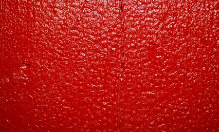 Old shiny board painted in red paint. Cracks, chips, bumps, drips of paint.の写真素材