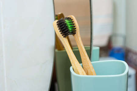 Two kissing toothbrushes in a cup against the background of a mirror.の写真素材