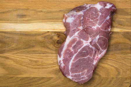A piece of raw pork meat on a cutting board. View from above.の写真素材