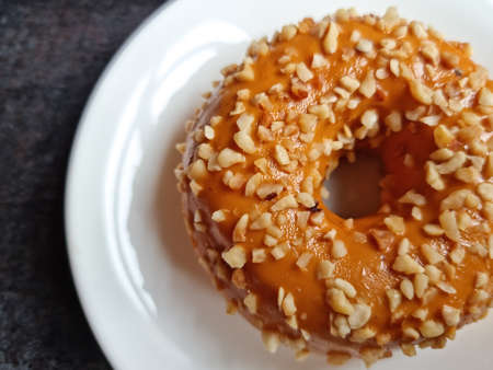 Delicious pastries. Donut covered with caramel and nuts on a white plate.の写真素材