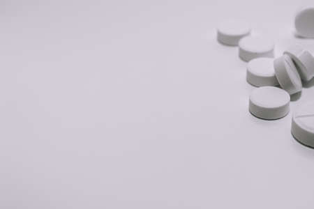 Several white pills on a white background in the upper corner of the photo. Black and white photo. Selective focus. Medical theme.の写真素材