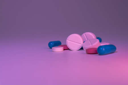 A pile of medical pills on a gray-pink background. Medications. Selective focus.の写真素材