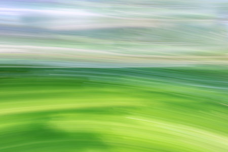 Hills of green fields and sky. Spring summer landscape. Abstract background. The photo was taken with the movement of the camera at a long exposure.の写真素材