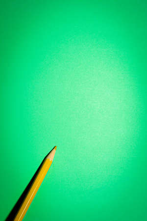 One yellow pencil on a vertical paper green background.の写真素材