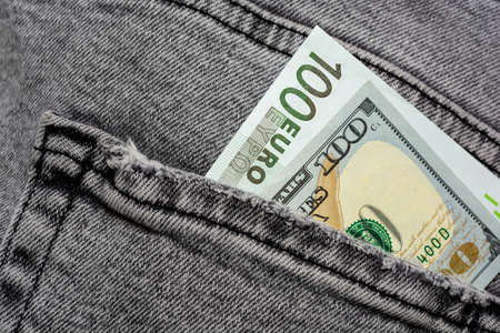 American hundred dollars and 100 euros in the back pocket of frayed jeans. Choice in currency exchange. Selective focus.の写真素材
