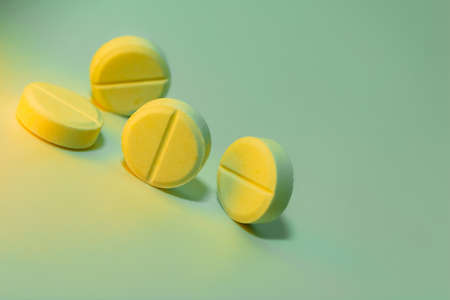 Yellow pills on a light green background. Place for your text. Close-up. Selective focus. Healthcare and medical concept.の写真素材