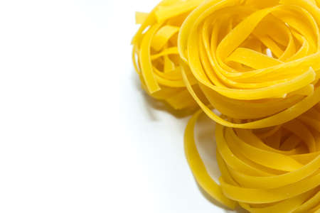 Italian pasta made from durum wheat flour on a white background. Close-up, top view. Selective focus. Tagliatelleの写真素材