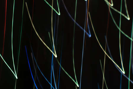 Bright multicolored diagonal V shaped beams of glare on black in cool tones. Abstract dark...