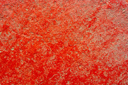 Red cracked paint background on gray concrete. Old plaster finish.