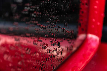 Water drops on a red car mirror close-up. abstraction.の写真素材
