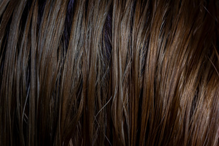 Close up background of wet female hair after bathing with shampoo, warm brown colors. Selective...