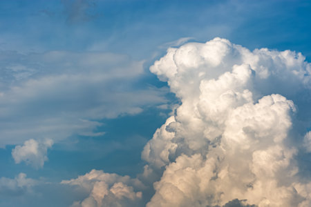 Blue sky against a background of white clouds. Cumulus clouds close-up at sunset. Natural background.の写真素材