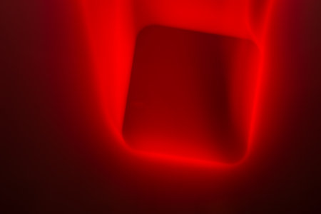 An abstract image showing a bold, luminous red square set against a deep red and black background. The edges of the square are soft, blending into the surrounding colors, creating a striking visual effect.の写真素材