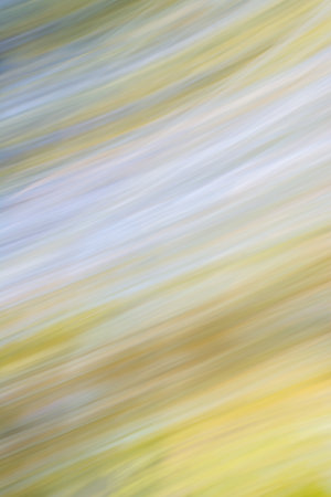 Abstract image with blurred diagonal lines in shades of yellow, green and blue. The sense of...